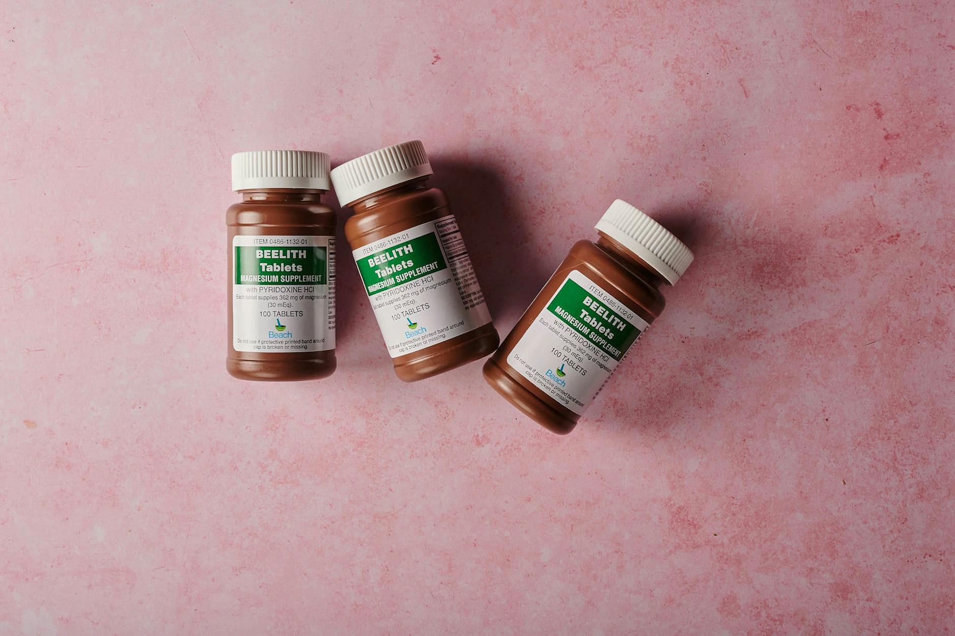 Three brown bottles of magnesium tablets on a soft pink background, ideal for health-themed content. (Photo by Beelith USA on Pexels)