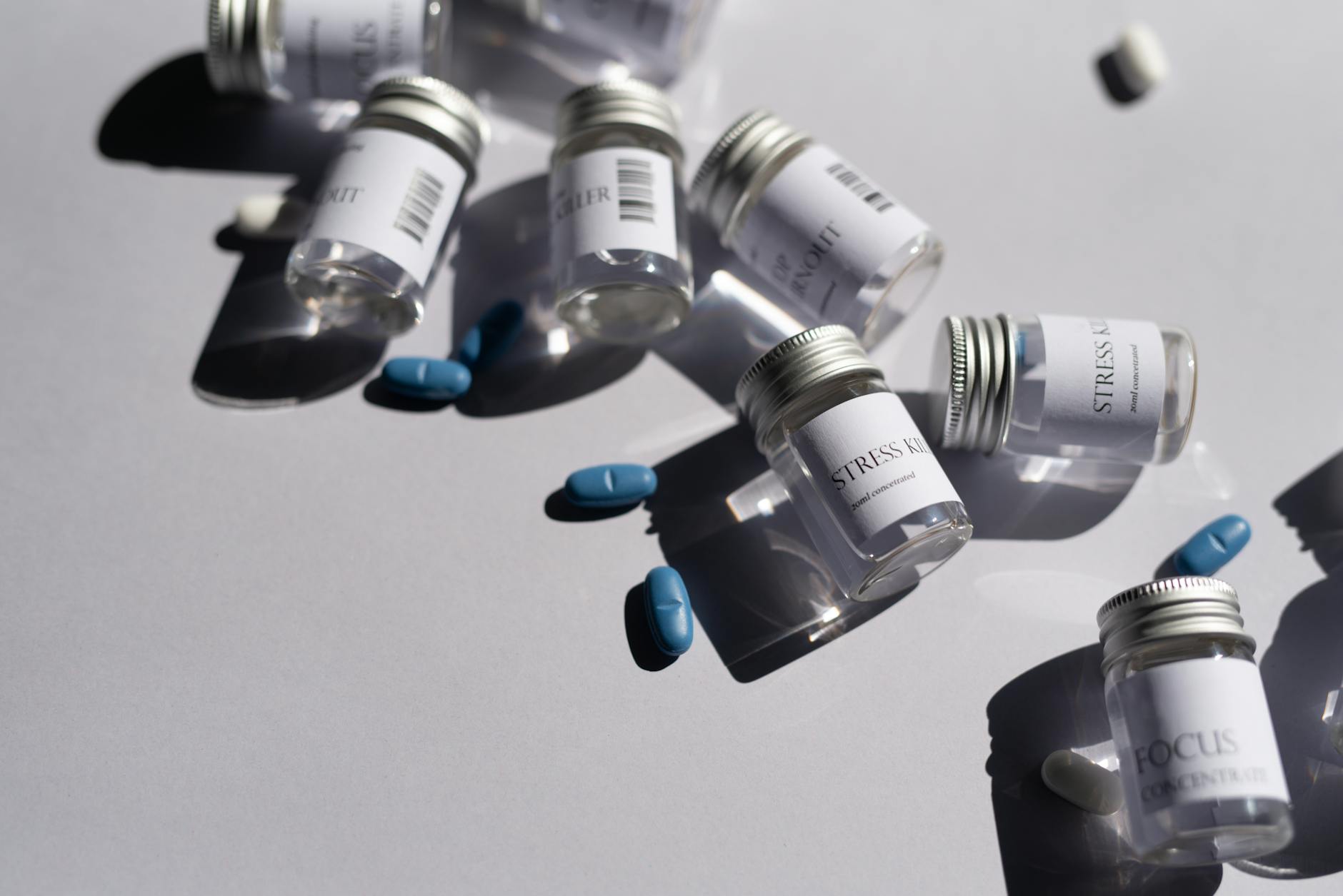 Close-up of medicine bottles and blue pills on a white background, emphasizing healthcare. (Photo by Leeloo The First on Pexels)