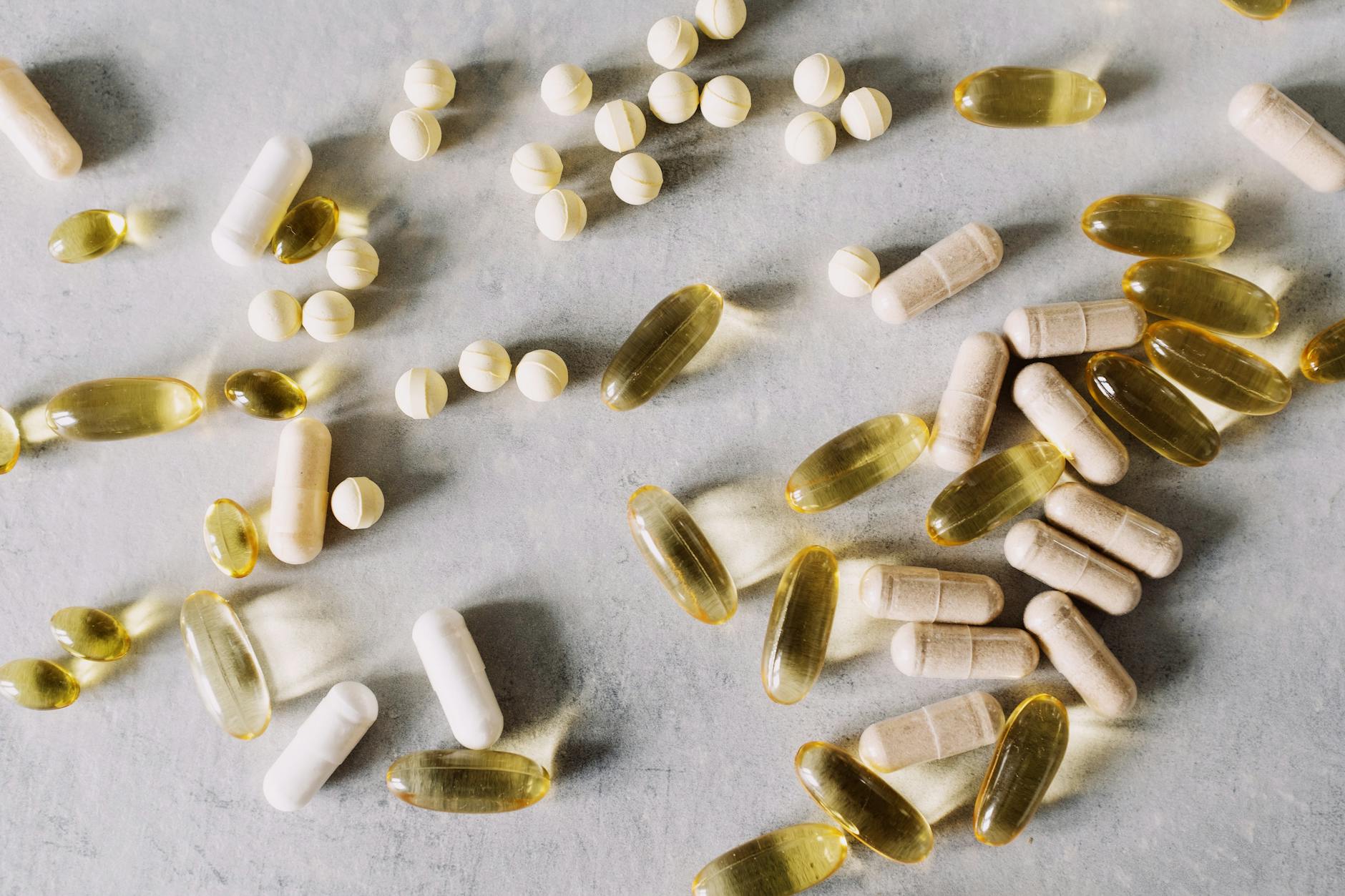 Various vitamins and supplements on a marble background, captured in flat lay style. (Photo by ready made on Pexels)