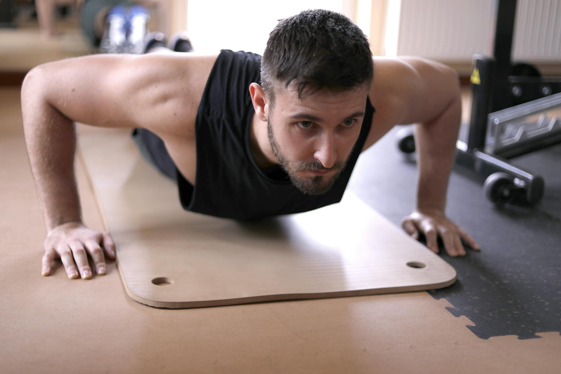 A dedicated adult man doing push-ups on a mat in a gym setting. (Photo by Andrea Piacquadio on Pexels)