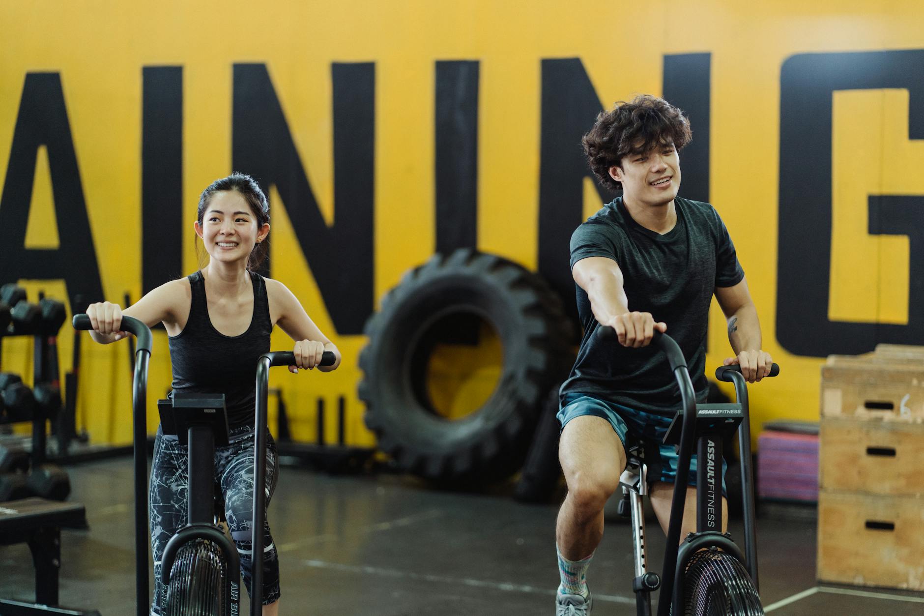 Happy couple enjoying an indoor cycling workout together, enhancing fitness and having fun. (Photo by Ketut Subiyanto on Pexels)