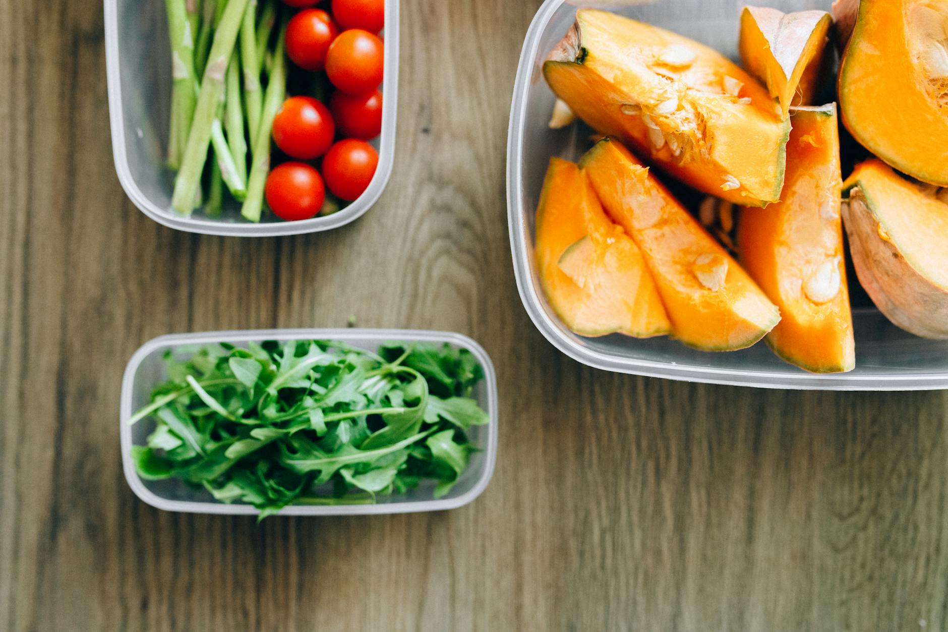Top view of fresh ingredients including arugula, cherry tomatoes, and squash in plastic container... (Photo by Nataliya Vaitkevich on Pexels)