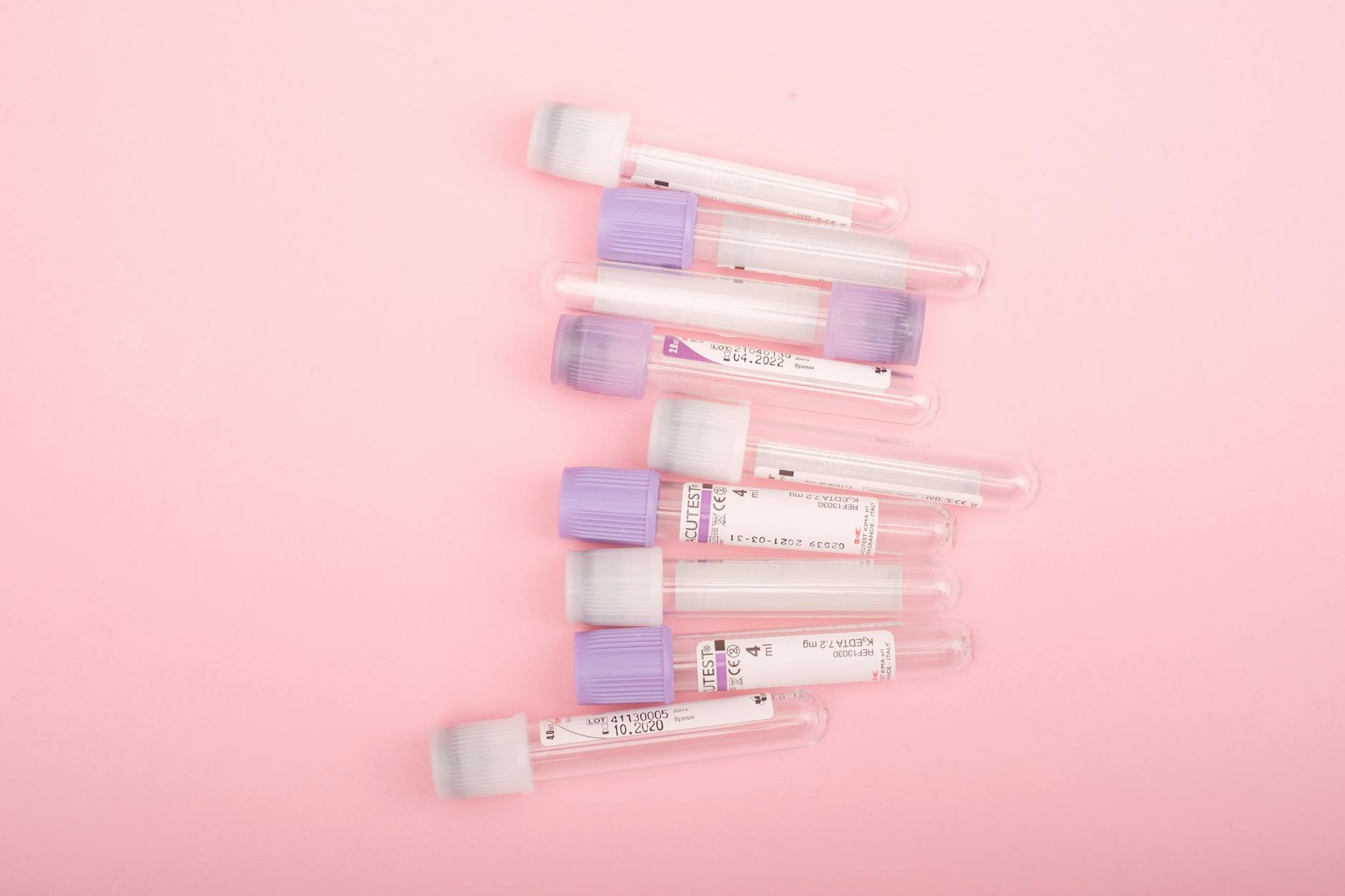 Top view of transparent glass test tubes with stickers placed on pink background (Photo by Alena Shekhovtcova on Pexels)