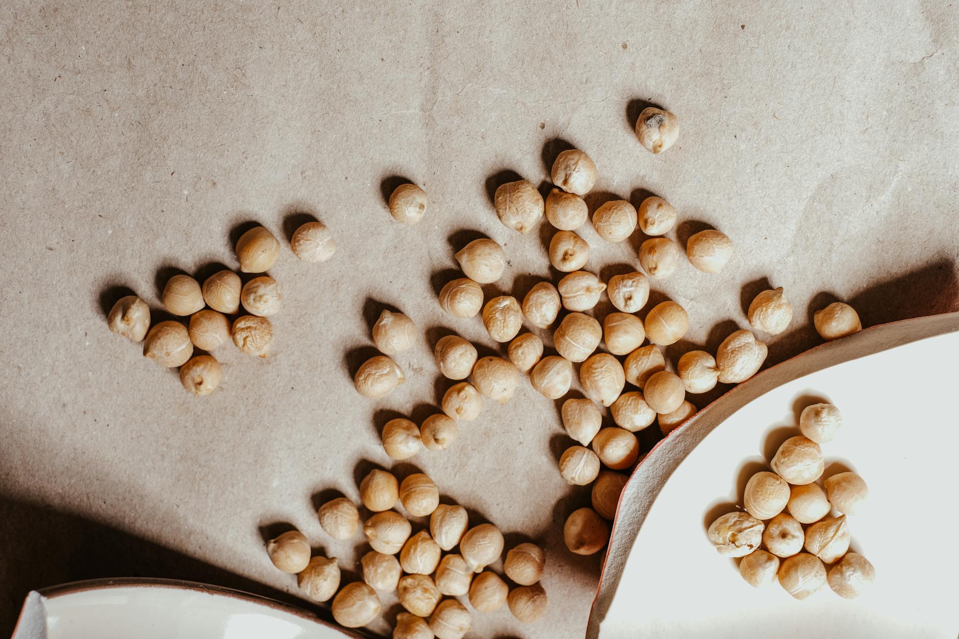 Close-up of dried chickpeas scattered on a textured brown surface, perfect for healthy food imagery. (Photo by Vie Studio on Pexels)