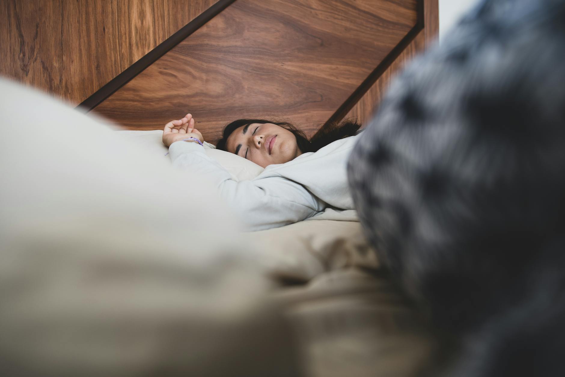 A woman peacefully sleeping on a bed, conveying relaxation and comfort. (Photo by Los Muertos Crew on Pexels)