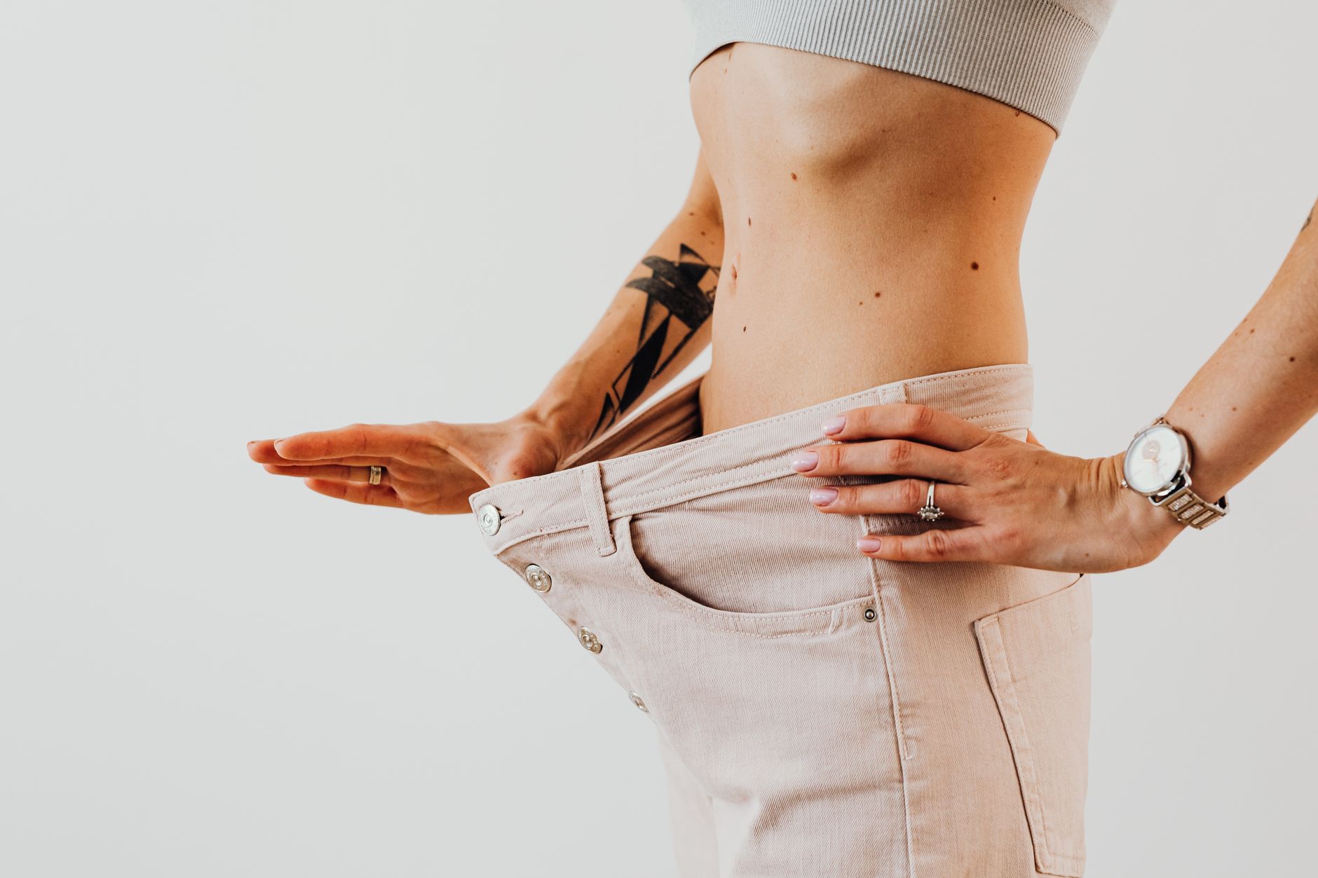 Close-up of a woman in oversized pants showcasing weight loss progress. Studio shot with neutral ... (Photo by www.kaboompics.com on Pexels)