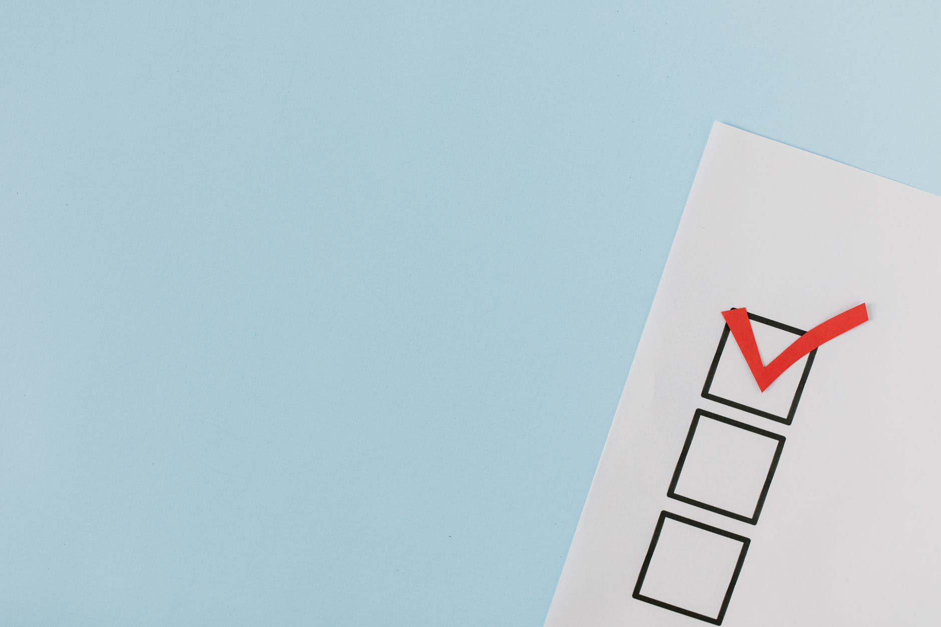 A checklist with a red checkmark symbolizing a completed task on a pastel blue background. (Photo by Tara Winstead on Pexels)